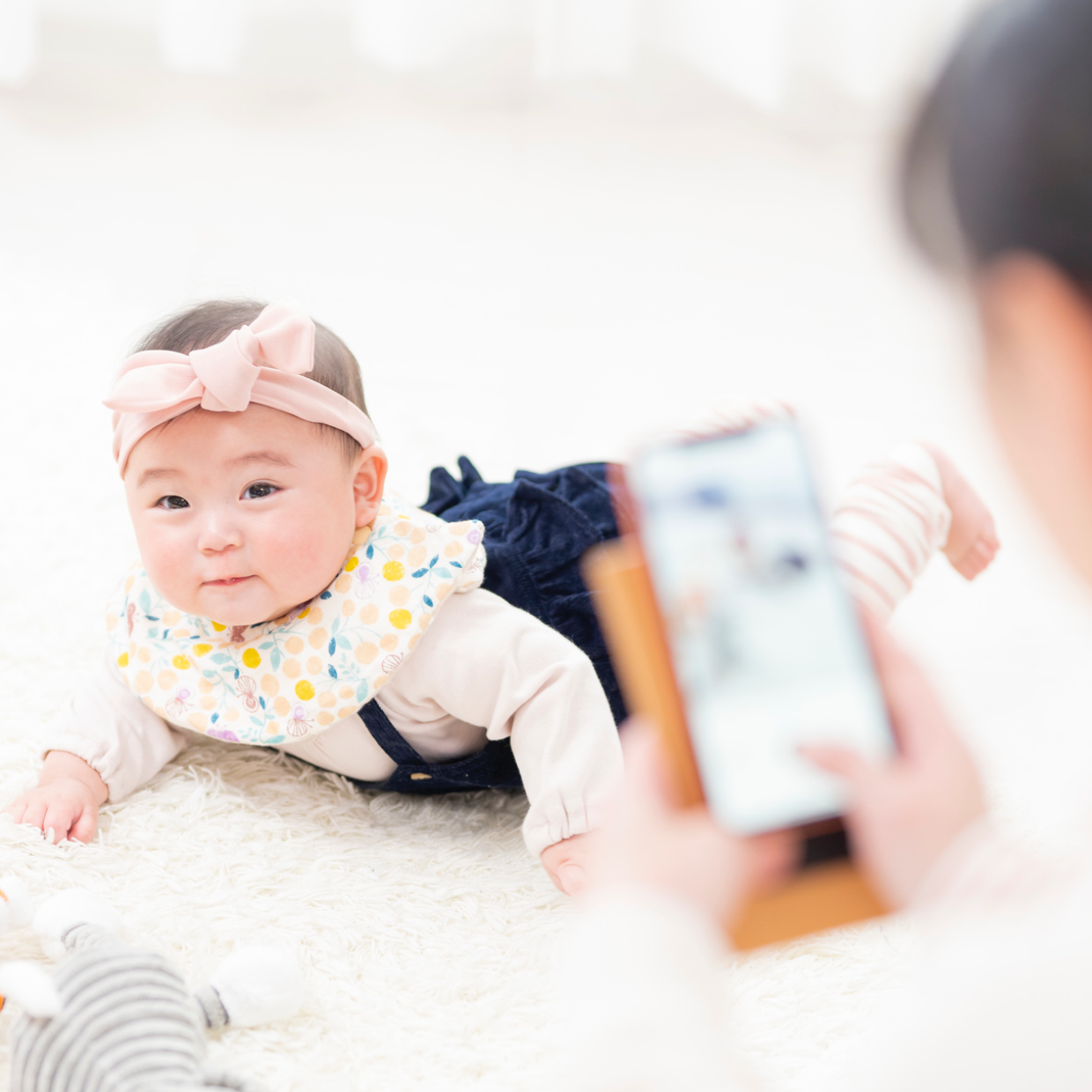 ハチマキを巻いた赤ちゃんをスマホで撮影するお母さん